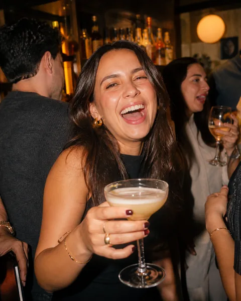 Femme riant avec un cocktail en soirée